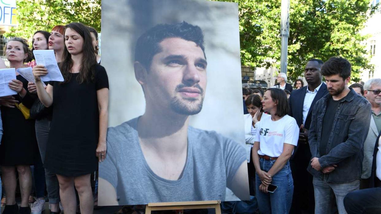 BFM TV journalist Maxime Brandstaetter (R), who was in Ukraine with his colleague Frederic Leclerc-Imhoff, stands with mourners next to a portrait of French journalist killed in Ukraine Frederic Leclerc-Imhoff during a tribute rally on the Place de la Republique in Paris, on June 10, 2022. - French BFM TV news channel journalist Frederic Leclerc-Imhoff was killed in eastern Ukraine on June 1, 2022, while on board a humanitarian bus with civilians fleeing Russian bombardment. (Photo by Bertrand GUAY / AFP)