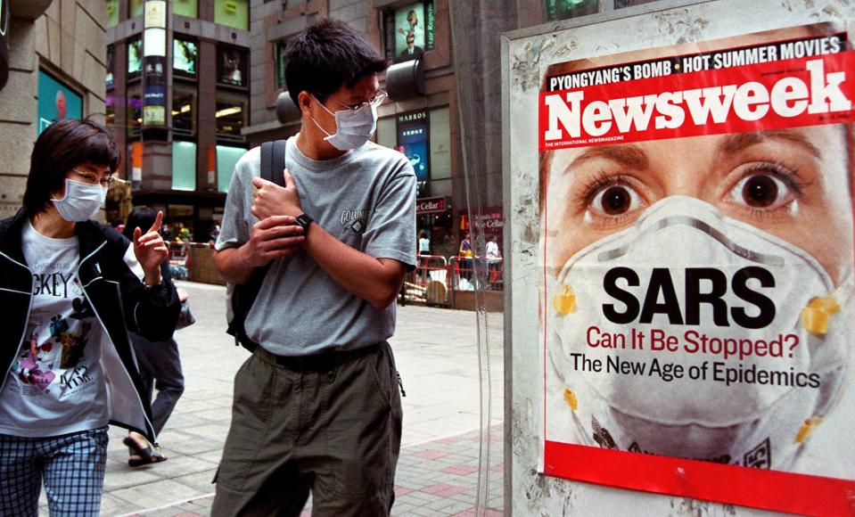 A man wearing a surgical mask in a Hong Kong street Friday, May 2, 2003, because of the outbreak of severe acute respiratory syndrome, stops to look at a magazine poster that has SARS as its cover story.