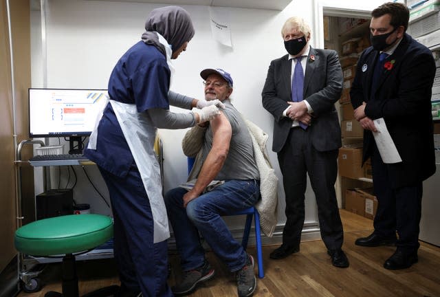 Prime Minister Boris Johnson watches a man receiving a coronavirus vaccination at a pharmacy in Sidcup