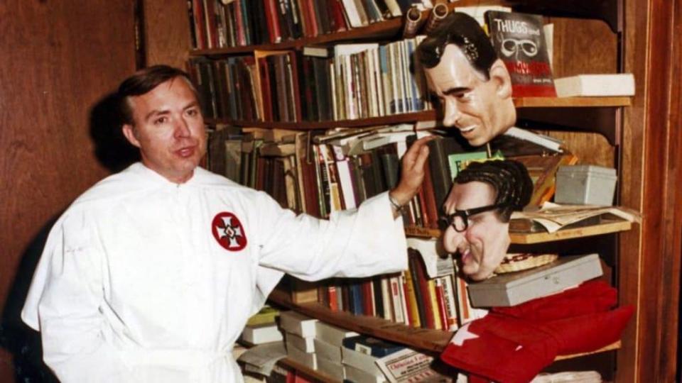 This May 12, 1977, photo shows white supremacist and former Ku Klux Klan leader Tom Metzger in San Diego. At right are masks of former president Richard Nixon, top, and former Secretary of State Henry Kissinger. Metzger, has died at age 82. The Riverside County Public Health Department said Thursday, Nov. 12, 2020, that Metzger died Nov. 4 of Parkinson’s disease. (The San Diego Union-Tribune via AP)