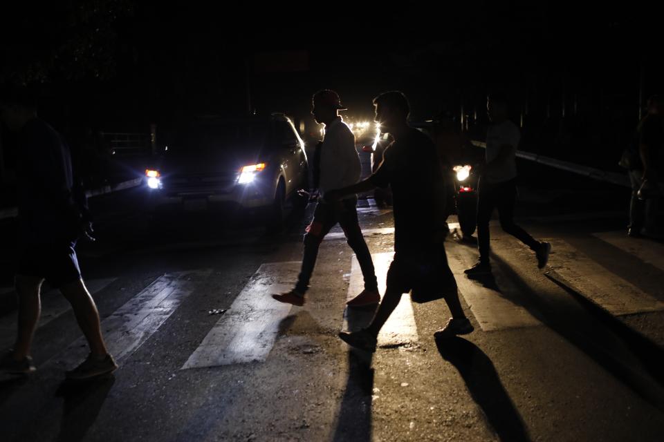 People walk on a street during a blackout in Caracas, Venezuela, Monday, July 22, 2019. The lights went out across much of Venezuela Monday, reviving fears of the blackouts that plunged the country into chaos a few months ago as the government once again accused opponents of sabotaging the nation's hydroelectric power system. (AP Photo/Ariana Cubillos)