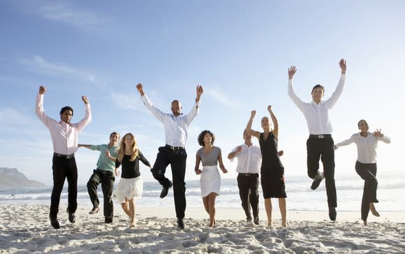 Business people jump for joy on a beach.