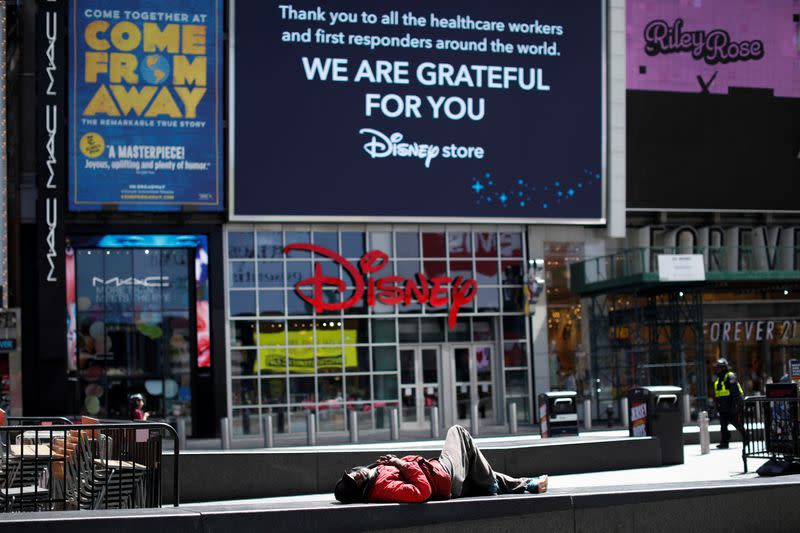 A man sleeps beneath a sign thanking healthcare workers in nearly empty Times Square during outbreak of the coronavirus disease (COVID-19) in New York