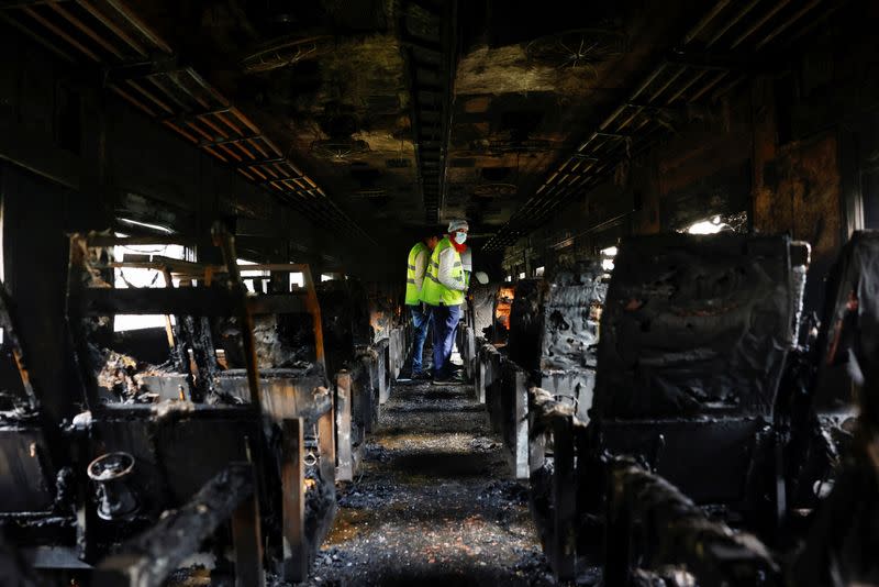 Crime Scene Unit members inspect the passenger train that was set on fire during a countrywide strike called by the Bangladesh Nationalist Party, in Dhaka