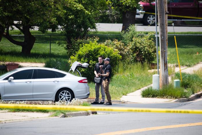 Layton Police officers gather around the trunk of a car near the scene of a triple homicide in Layton on May 19, 2023. | Ryan Sun, Deseret News
