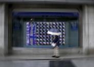 A woman holding an umbrella looks at an electronic stock quotation board outside a brokerage in Tokyo September 8, 2015. REUTERS/Issei Kato