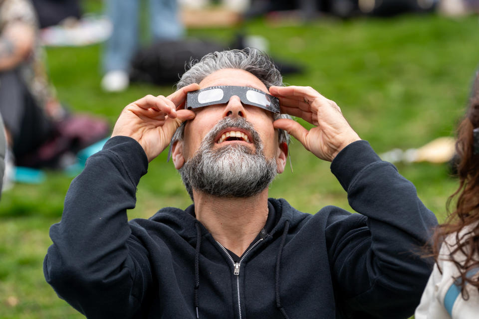 A man watches the beginning of the partial solar eclipse at Riverdale Park, wearing his special eclipse glasses. On April 8, 2024, Toronto witnessed a partial solar eclipse, with around 85% coverage of the sun. Skywatchers in the city observed the moon passing between the Earth and the sun, creating a noticeable dimming of sunlight during the event. (Photo by Shawn Goldberg/SOPA Images/LightRocket via Getty Images)