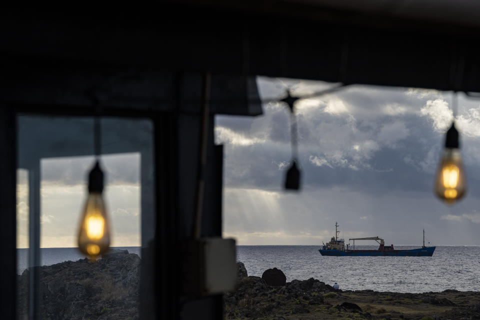 A ship that supplies Easter Island with products from Chile's mainland is anchored off Hanga Roa, Rapa Nui, seen from a restaurant, Sunday, Nov. 27, 2022. The quickest way to get here is a six-hour flight from Santiago, Chile. (AP Photo/Esteban Felix)