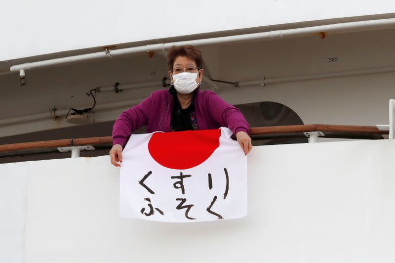 Una mujer sostiene una bandera japonesa que dice "faltan medicamentos" en el crucero Diamond Princess.