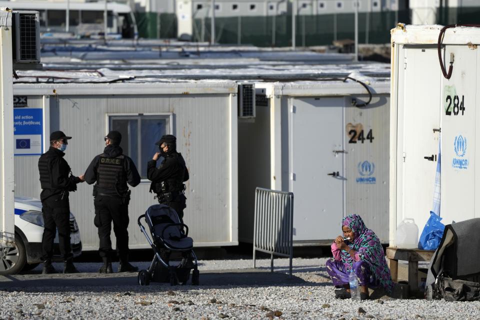 A migrant brushes her teeth as police secure the area before the visit of Pope Francis at the Karatepe refugee camp, on the northeastern Aegean island of Lesbos, Greece, Sunday, Dec. 5, 2021. Pope Francis is returning to Lesbos, the Greek island that was at the heart of a massive wave of migration into Europe six years ago, after making pointed criticism of European governments on the handling of the crisis during a visit to two hard-hit countries. (AP Photo/Alessandra Tarantino)