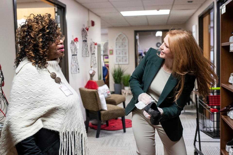 Jenna Holt, Chevrolet assistant retail planning manager who volunteers at Dress for Success Michigan, talks to Cathleen Taylor, CEO of Dress for Success Michigan, while wiping down shoes at the warehouse in Ypsilanti on Tuesday, Dec. 12, 2023.