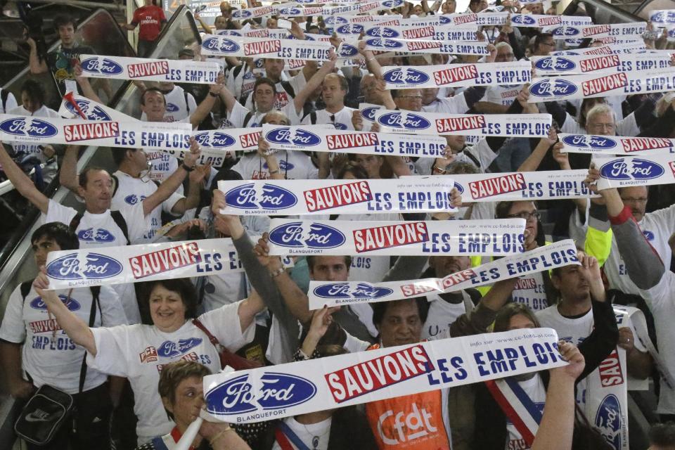 Workers from a Ford factory in France, holding giant stickers that read: "Save the Jobs", protest against factory policy as they march through the Paris Auto Show, France, Saturday, Sept. 29, 2012. The workers swarmed the Paris Auto Show with giant stickers, plastering about 20 cars around the hall to protest lost jobs in the automotive industry. (AP Photo/Michel Euler)