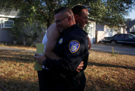 Calvin Sanders hugs Santa Rosa police officer Travis Dunn while receiving a pass that allows him to come and go from the evacuation zone he lives in after a wildfire tore through adjacent streets in Santa Rosa, California, U.S. October 15, 2017. REUTERS/Jim Urquhart