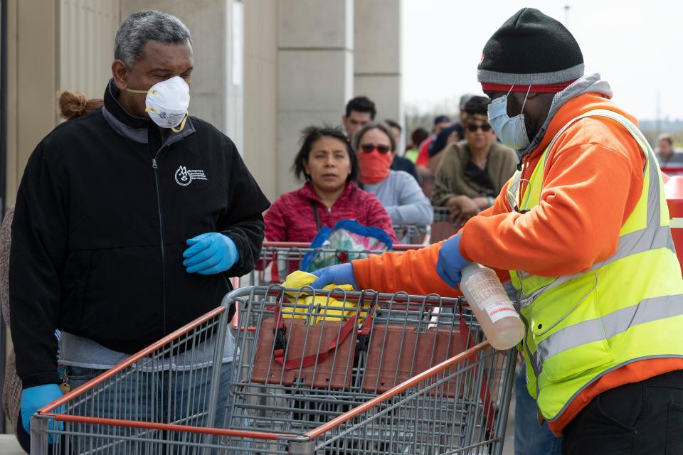 A Costco employee disinfects a shopping cart as shoppers line up to get into the bulk shopping store in Washington, DC, on April 5, 2020. - The number of confirmed coronavirus, COVID-19,  cases in the United States has topped 300,000 and there have been more than 8,100 deaths, Johns Hopkins University reported on Saturday. (Photo by JIM WATSON / AFP) (Photo by JIM WATSON/AFP via Getty Images)