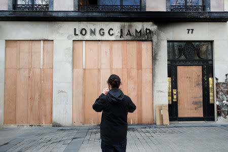 A man takes pictures of a Longchamp shop damaged during the last "yellow vests" protest on the Champs Elysees avenue in Paris, France, March 18, 2019. REUTERS/Philippe Wojazer