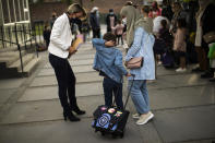 FILE - In this Tuesday, Sept. 1, 2020 file photo, a child and his mother are welcomed by the director of the primary school during the first day of classes in Brussels. The European Union executive announced Thursday, March 4, 2021 that it wants to force employers to be much more open about how much money staff makes to make it easier for women to challenge wage imbalances and further closer the gender pay gap. The EU made it clear that women workers had been disproportionally affected by the pandemic, many having to add more home tasks to their work schedule because of closure of schools and day care centers. (AP Photo/Francisco Seco, File)