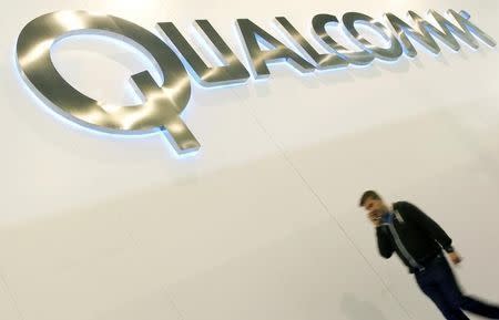 A man walks past a Qualcomm advertising logo at the Mobile World Congress at Barcelona, February 27, 2013. REUTERS/Albert Gea