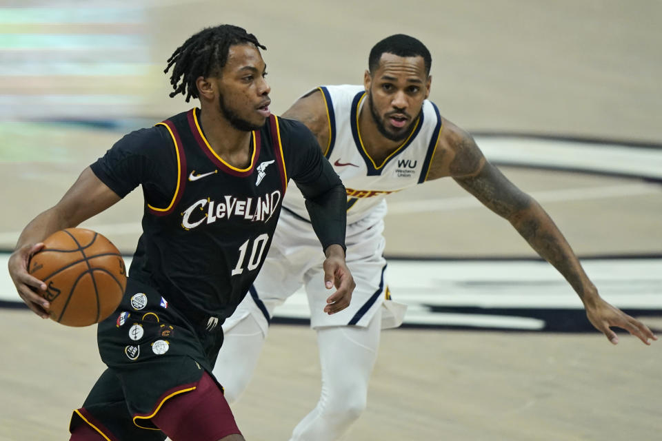 CORRECTS DENVER PLAYER TO MONTE MORRIS, INSTEAD OF WILL BARTON - Cleveland Cavaliers' Darius Garland, left, drives past Denver Nuggets' Monte Morris during the first half of an NBA basketball game Friday, Feb. 19, 2021, in Cleveland. (AP Photo/Tony Dejak)