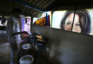 A worker prepares a traditional snack next to a banner featuring U.S. Vice President-elect Kamala Harris, lying outside a local eatery in Thulasendrapuram, the hometown of Harris' maternal grandfather, south of Chennai, Tamil Nadu state, India, Wednesday, Jan. 20, 2021. A tiny village in a remote part of South India is gearing up for celebrations ahead of Kamala Harris’ inauguration as the first female vice president of the United States. (AP Photo/Aijaz Rahi)