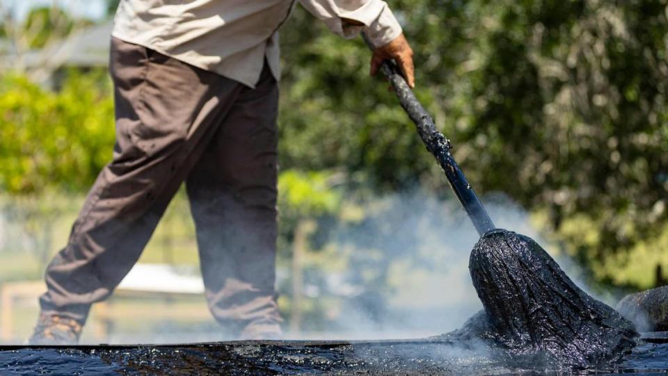 Gilberto Lujano, de 49 años, esparciendo alquitrán en un tejado el martes 2 de mayo de 2023, en Homestead, la Florida.