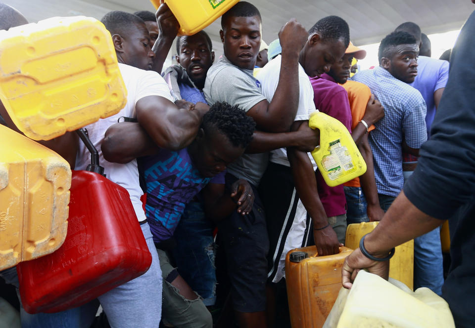 FILE - In this Sept. 4, 2019 file photo, people fight as they line up at a closed gas station, hoping it will open eventually, during a fuel shortage in Port-au-Prince, Haiti. Despite the rarity of his public appearances, Haiti’s embattled president has given no indication he will step down amid nearly a month of demonstrations against corruption, spiraling inflation and dwindling supplies of food and gasoline. (AP Photo/Dieu Nalio Chery, File)