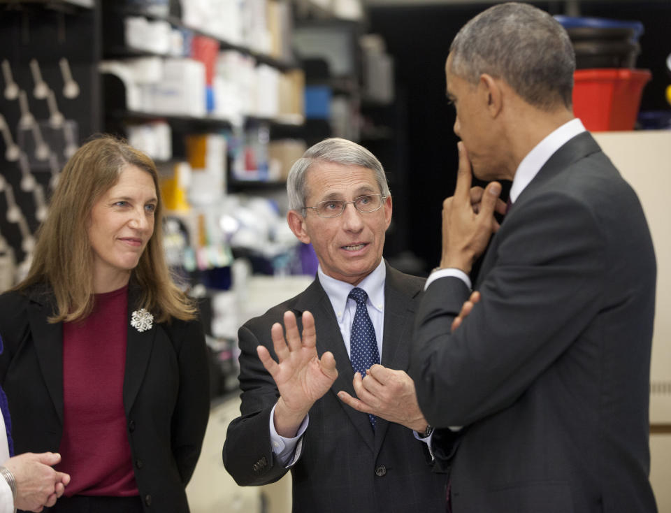 FILE - Dr. Anthony Fauci, center, director of NIH's National Institute of Allergy and Infectious Diseases, talks with President Barack Obama, right, as Sylvia Mathews Burwell, left, Secretary of Health & Human Services, looks on during a tour of the Vaccine Research Center at the National Institutes of Health, Dec. 2, 2014 in Bethesda, Md. Fauci steps down from a five-decade career in public service at the end of the month, one shaped by the HIV pandemic early on and the COVID-19 pandemic at the end. (AP Photo/Pablo Martinez Monsivais, File)