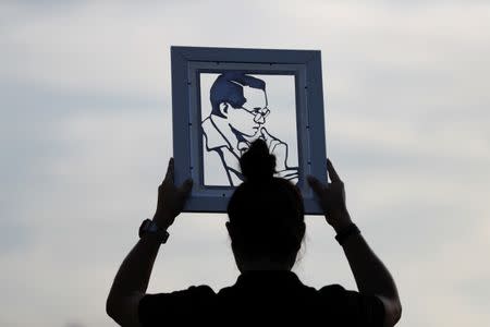 A woman holds the portrait of Thailand's late King Bhumibol Adulyadej as mourners wait for tomorrow's Royal Cremation ceremony near the Grand Palace in Bangkok. REUTERS/Damir Sagolj