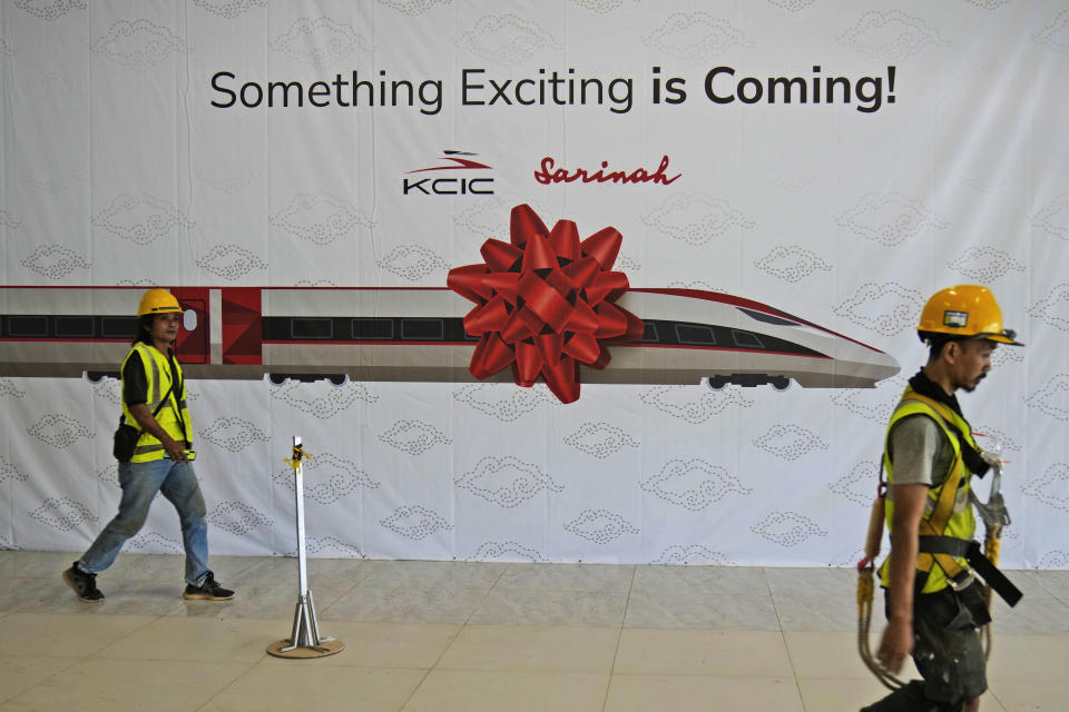 FILE - Workers walk past a banner at the construction site of Halim Station ahead of an operational test run of the Jakarta-Bandung high-speed train, which is part of China's Belt and Road infrastructure initiative, in September, in Jakarta, Indonesia, on Aug. 12, 2023. China's Belt and Road initiative has built power plants, roads, railroads and ports around the world and deepened China's relations with Africa, Asia, Latin America and the Mideast. It is a major part of Chinese President Xi Jinping's push for China to play a larger role in global affairs. (AP Photo/Dita Alangkara, File)