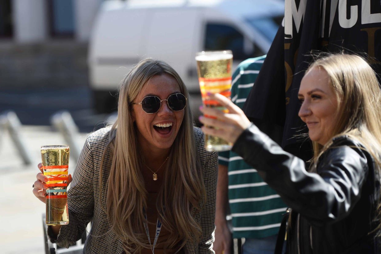 'A good news week for the UK': People enjoy a drink in Belfast on Friday. (PA)