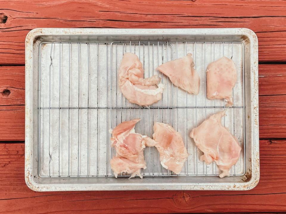 pieces of raw chicken on a wire rack on a sheet pan