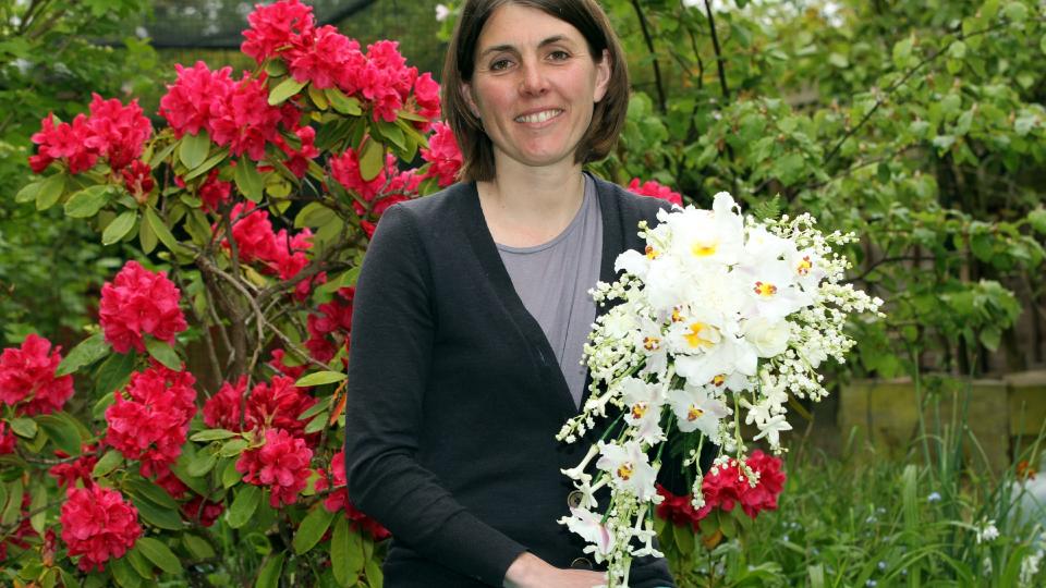 ILFORD, ENGLAND - MAY 29: Lottie Longman of Longman's Florists poses with a replica of the Coronation bouquet, which is to be presented to Queen Elizabeth II in celebration of the 60th anniversary of her Coronation on May 29, 2013 in Ilford, England. Lottie is the granddaughter of the late Martin Longman, of Longman's florists, who made the original bouquet for the monarch in 1953, used photos from the Coronation Day and an oil painting of the flowers to help her recreate the exact bouquet. The celebrations begin on June 02, 2013.