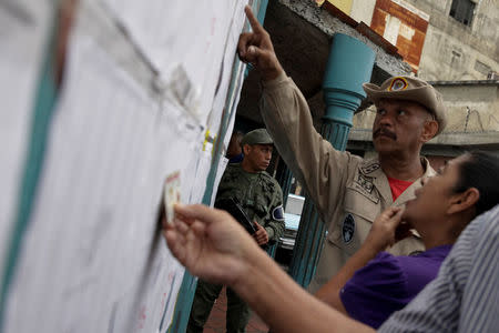 People check a list at a polling station during a nationwide election for new mayors, in Caracas, Venezuela December 10, 2017. REUTERS/Fabiola Ferrero