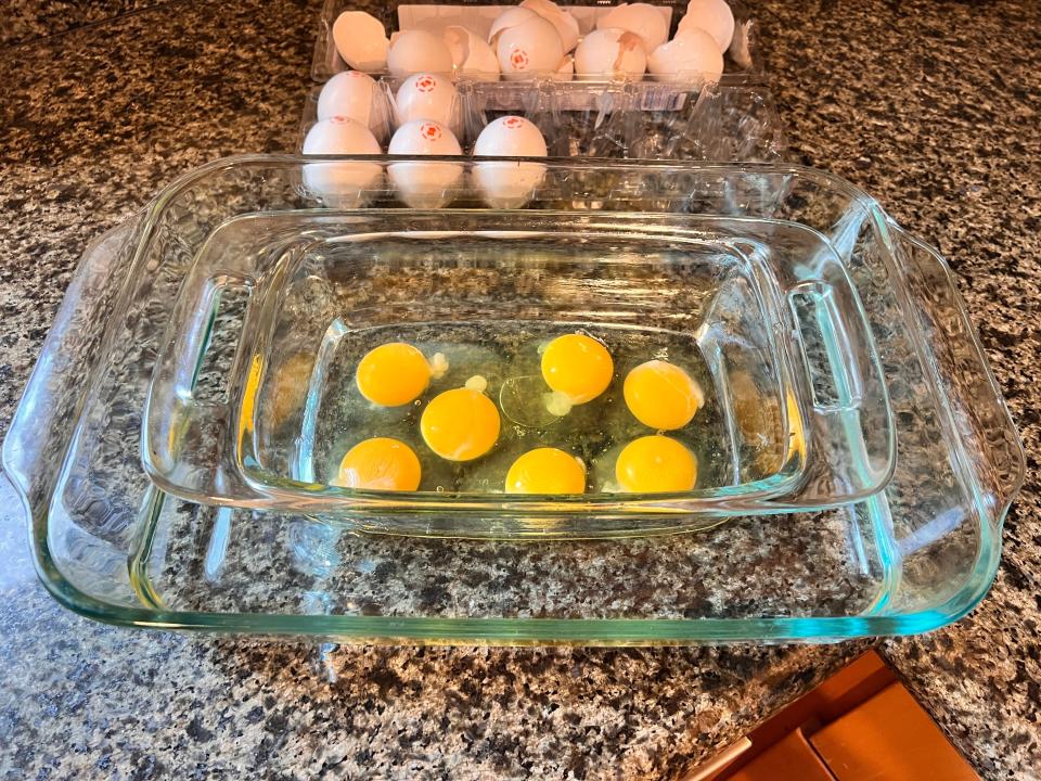 seven eggs cracked into a small loaf pan sitting in a larger baking dish