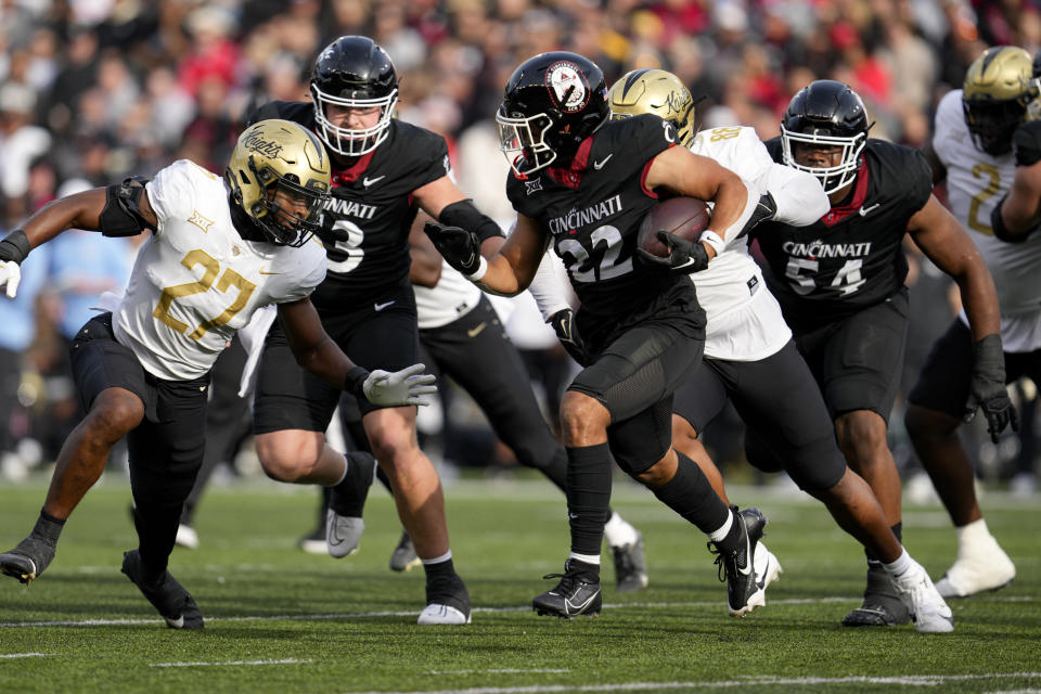 Cincinnati running back Ryan Montgomery (22) runs against Central Florida linebacker Walter Yates III (27) during the first half of an NCAA college football game, Saturday, Nov. 4, 2023, in Cincinnati. (AP Photo/Jeff Dean)