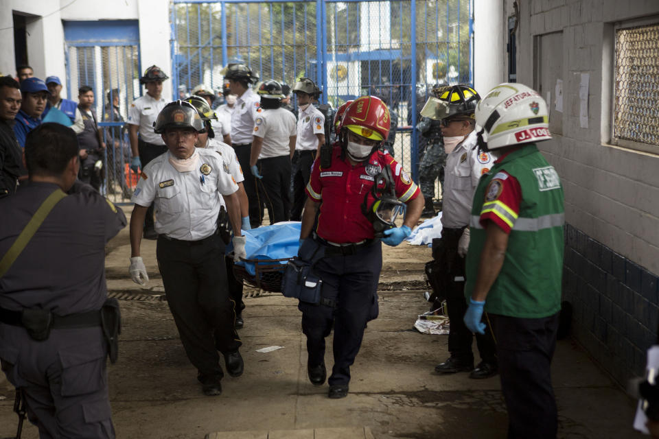 Firefighters carry the body of an inmate who died during a shooting inside the Pavon Rehabilitation Model Farm in Fraijanes, Guatemala, Tuesday, May 7, 2019. At least three people were killed and 10 people were wounded in the shooting, authorities said. (AP Photo/Oliver De Ros)