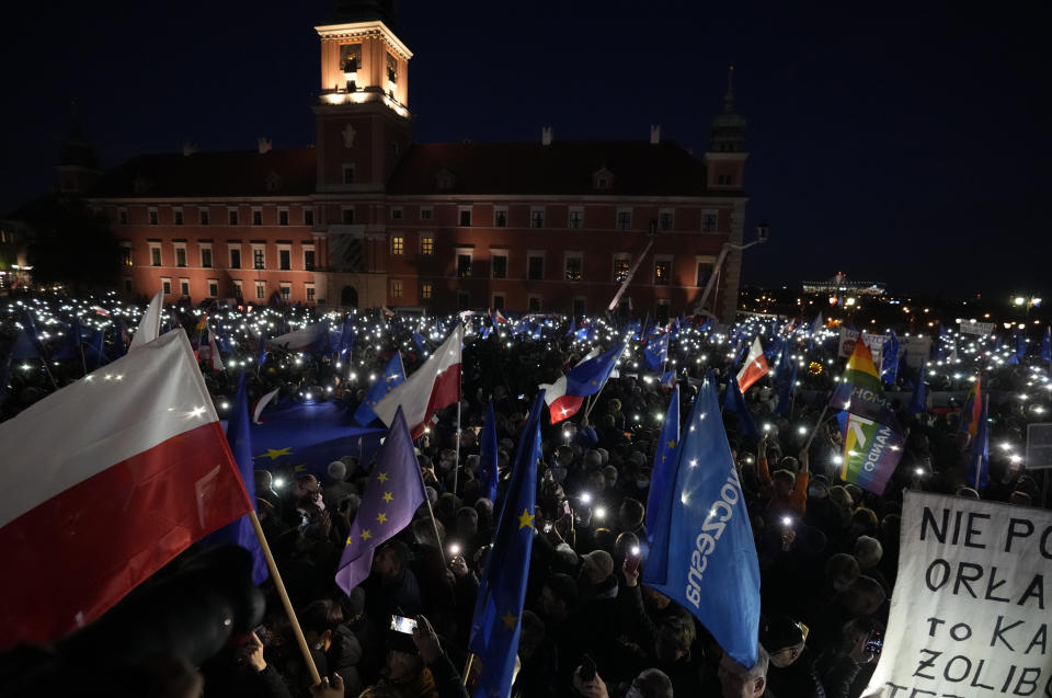 People hold up the flashlights of their mobile phones during a demonstration in support of Poland's EU membership in Warsaw, Poland, Sunday, October 10, 2021. Poland's constitutional court ruled Thursday that Polish laws have supremacy over those of the European Union in areas where they clash, a decision likely to embolden the country's right-wing government and worsen its already troubled relationship with the EU. Sign at center reads, 'One president, (AP Photo/Czarek Sokolowski)