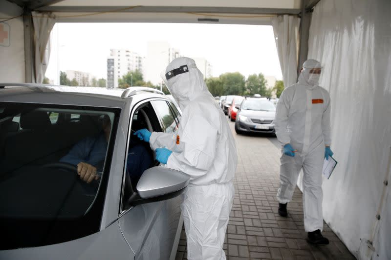A woman wearing protective coverall, performs tests for the coronavirus disease (COVID-19) at a drive-thru testing centre in Warsaw