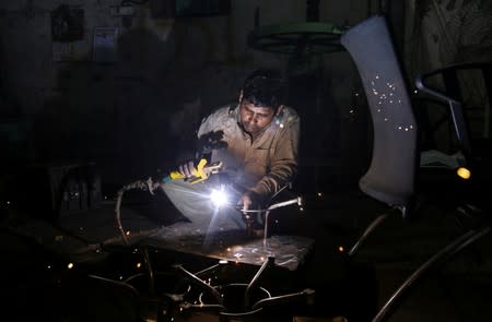 A worker welds an iron table stand at a workshop in Mumbai