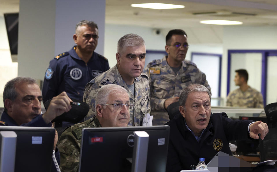 In this photo released by Turkey's defense ministry, Defense Minister Hulusi Akar, right, and top army commanders work at the Air Force command center, in Ankara, Turkey, early Sunday, Nov. 20, 2022. Turkey launched airstrikes over northern regions of Syria and Iraq, the Turkish Defense Ministry said Sunday, targeting Kurdish groups that Ankara holds responsible for last week's bomb attack in Istanbul. (Turkish Defense Ministry via AP)