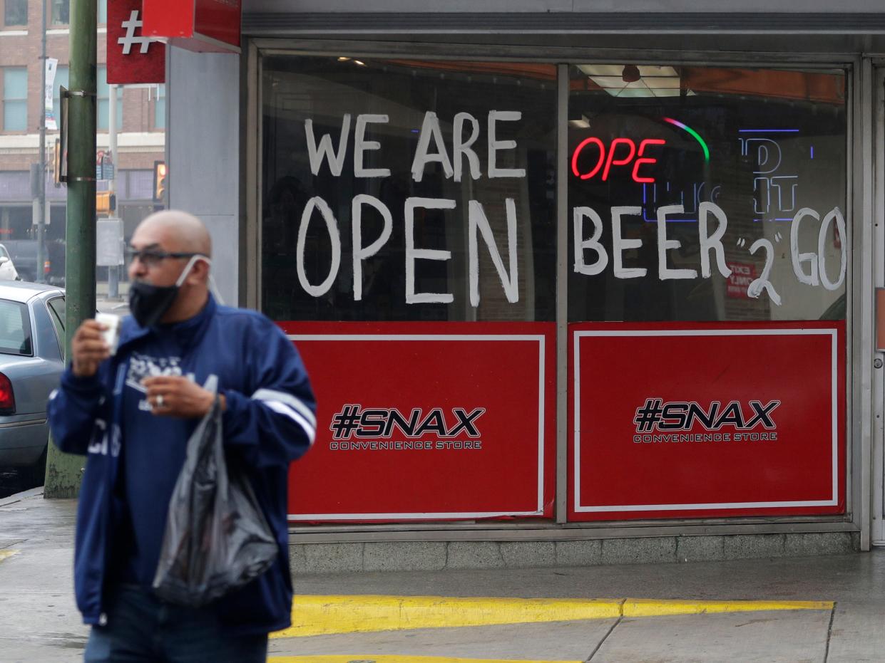 A man wears a face mask as he leaves a business that remains open in downtown San Antonio, Wednesday, April 22, 2020. San Antonio remains under stay-at-home orders due to the COVID-19 outbreak and residents are required to wear face coverings or masks whenever in public. (AP Photo/Eric Gay)