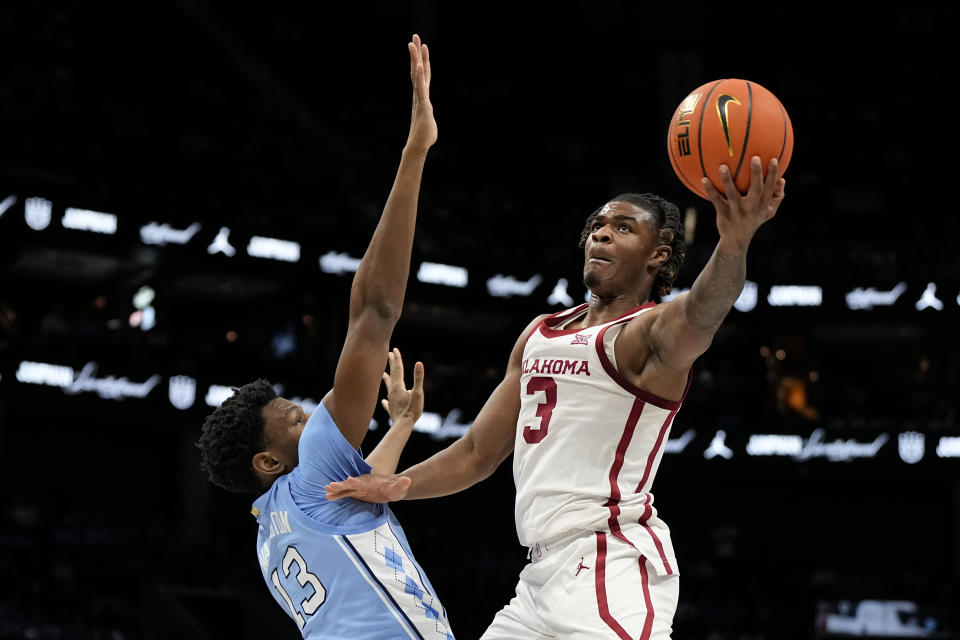 Oklahoma guard Otega Oweh shoots over North Carolina forward Jalen Washington during the first half of an NCAA college basketball game Wednesday, Dec. 20, 2023, in Charlotte, N.C. (AP Photo/Chris Carlson)