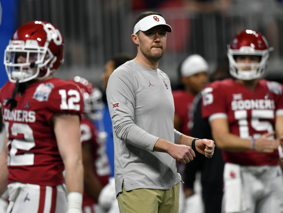 FILE - In this Dec. 28, 2019, file photo, Oklahoma head coach Lincoln Riley, center, stands with his team before the Peach Bowl NCAA semifinal college football playoff game against LSU in Atlanta. College football teams set to play this fall are trying to help their depth amid the coronavirus pandemic by finding players capable of playing multiple positions. Riley says it is “something every coach in the country is thinking about right now.” That's because positive tests, contact tracing and quarantines could abruptly alter any roster. (AP Photo/John Amis, File)