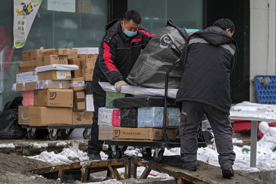 Workers of a private delivery company push a cart loaded with goods at its distribution center in Beijing, Sunday, Nov. 7, 2021. China's exports remained strong in October, a positive sign for an economy trying to weather power shortages and COVID-19 outbreaks. (AP Photo/Andy Wong)