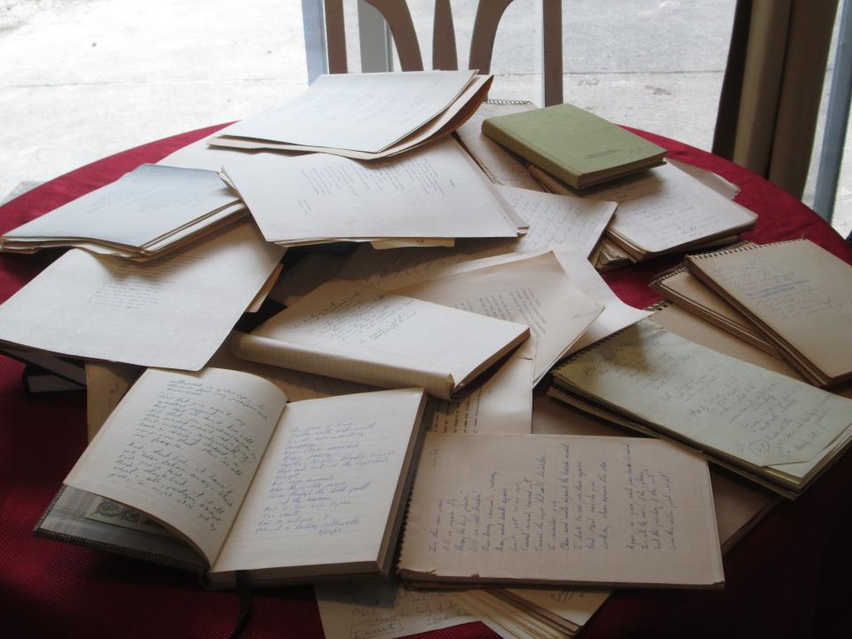 A stack of notebooks filled with poems crowds Marc Thomas' kitchen table.