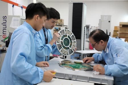 Employees of the automated test equipment designer and solutions provider Aemulus Holdings Berhad work at a production facility in Penang