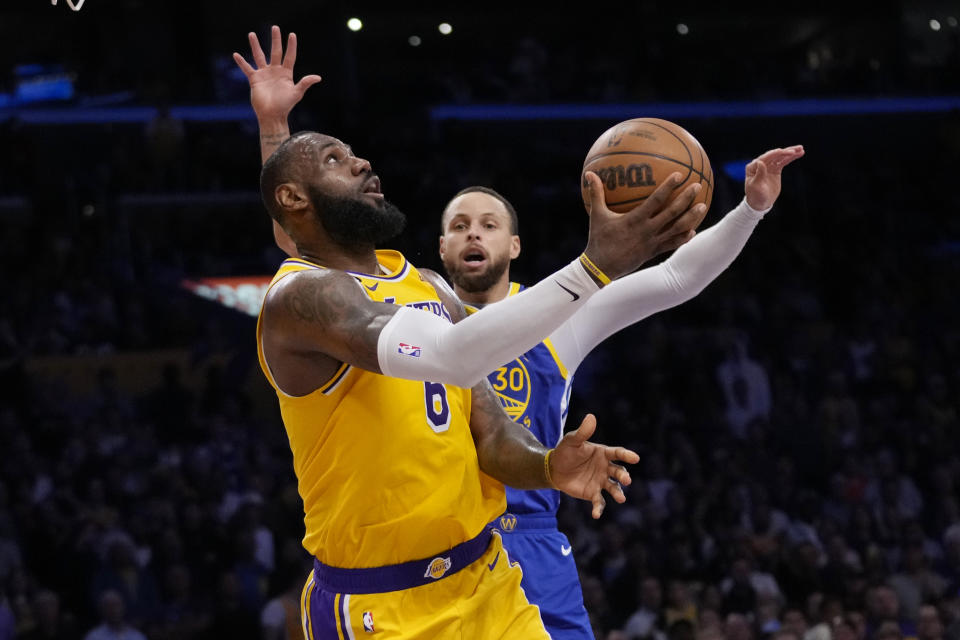 Los Angeles Lakers forward LeBron James scores past Golden State Warriors guard Stephen Curry during the second half in Game 6 of an NBA basketball Western Conference semifinal series Friday, May 12, 2023, in Los Angeles. (AP Photo/Ashley Landis)