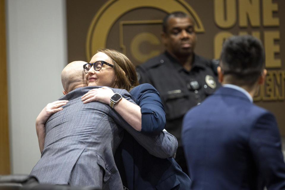 County teacher Katie Rinderle, center, hugs Brock Boone, an attorney with the Southern Poverty Law Center, during a hearing at the Cobb County Board of Education in Marietta, Ga, Thursday, Aug. 10, 2023. Rinderle is facing termination after reading "My Shadow is Purple," a book about gender identity, to fifth graders. (Arvin Temkar/Atlanta Journal-Constitution via AP)