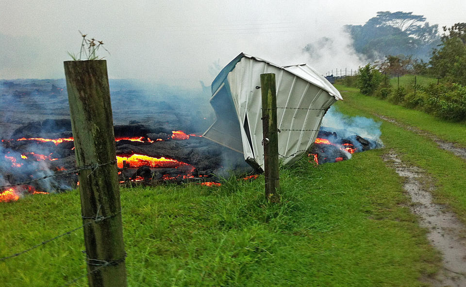 This Oct. 25, 2014 photo provided by the U.S. Geological Survey shows a small shed being consumed by lava in a pasture between the Pahoa cemetery and Apa?a Street near the town of Pahoa on the Big Island of Hawaii. Dozens of residents in this rural area of Hawaii were placed on alert as flowing lava continued to advance. Authorities on Sunday, Oct. 26, 2014 said lava had advanced about 250 yards since Saturday morning and was moving at the rate of about 10 to 15 yards an hour, consistent with its advancement in recent days. The flow front passed through a predominantly Buddhist cemetery, covering grave sites in the mostly rural region of Puna, and was roughly a half-mile from Pahoa Village Road, the main street of Pahoa. (AP Photo/U.S. Geological Survey)