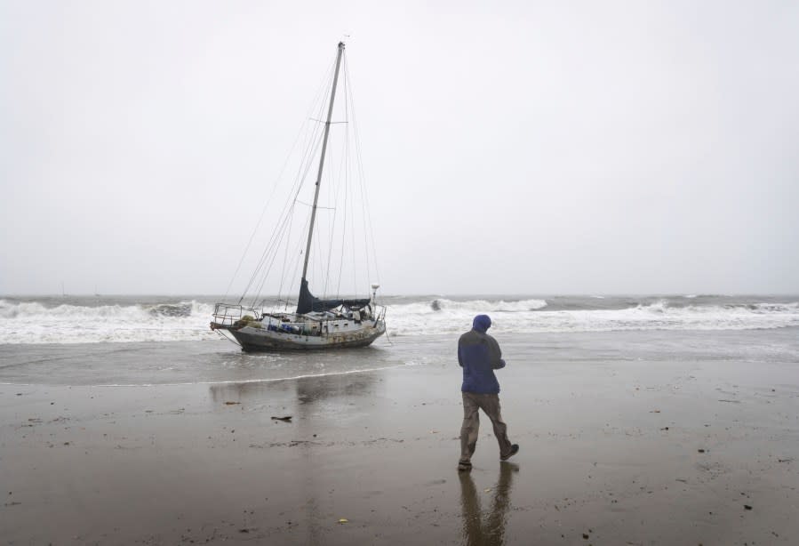 Stephen Wheeler, a Santa Barbara resident, walks past a drift boat that washed ashore during a rainstorm, Feb. 4, 2024, in Santa Barbara, Calif. Officials warned the second of back-to-back atmospheric rivers will cause possible life-threatening conditions. (AP Photo/Ethan Swope)