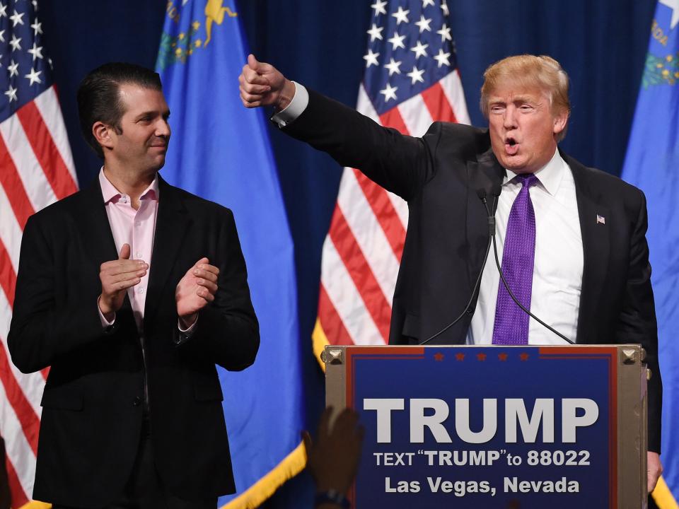 Donald Trump Jr. (L) looks on as his father, Republican presidential candidate Donald Trump, waves after speaking at a caucus night watch party at the Treasure Island Hotel & Casino on 23 February 2016 (Getty Images)